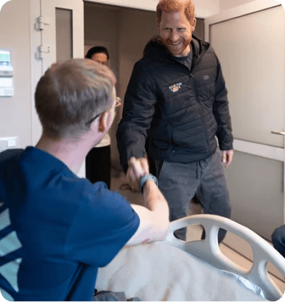 Prince Harry visiting a wounded defender in a hospital room